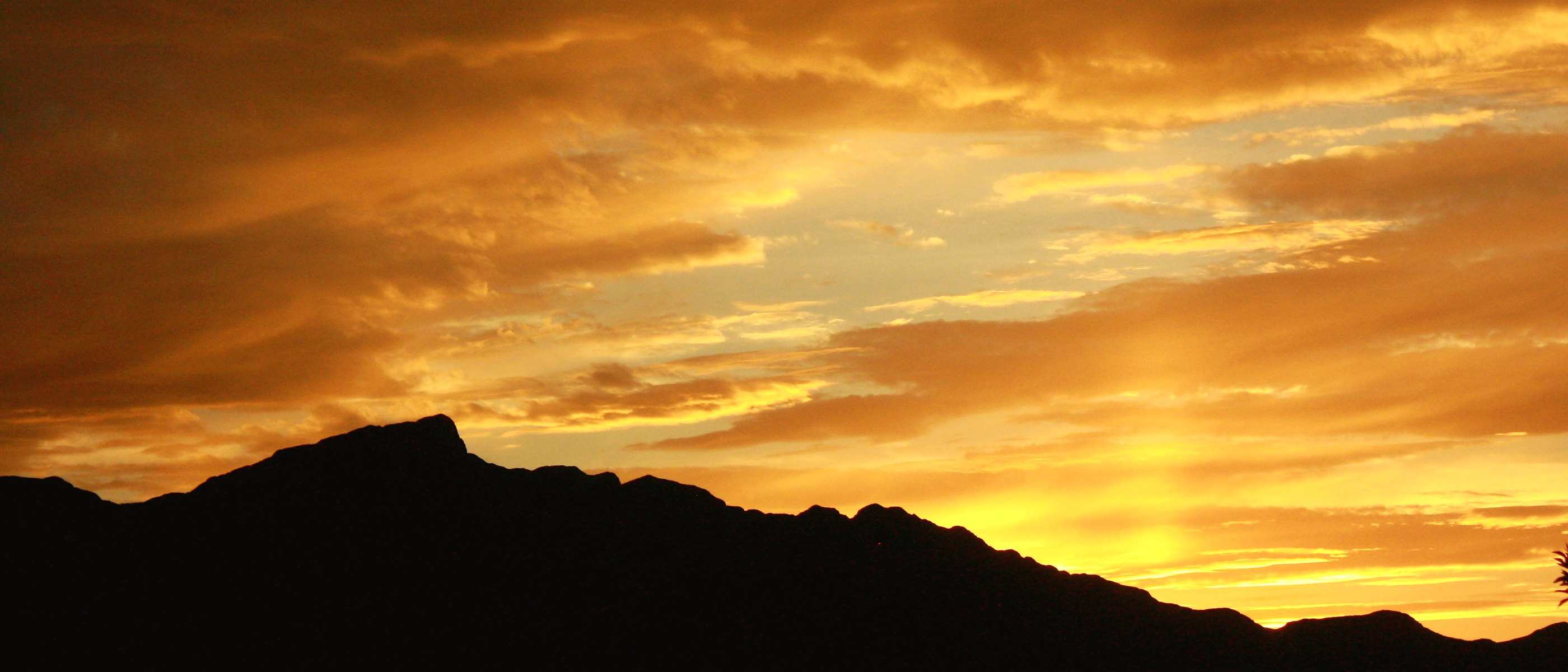 The north end of the Franklin Mountains silhouetted against a blazing orange sunset, seen from Northeast El Paso