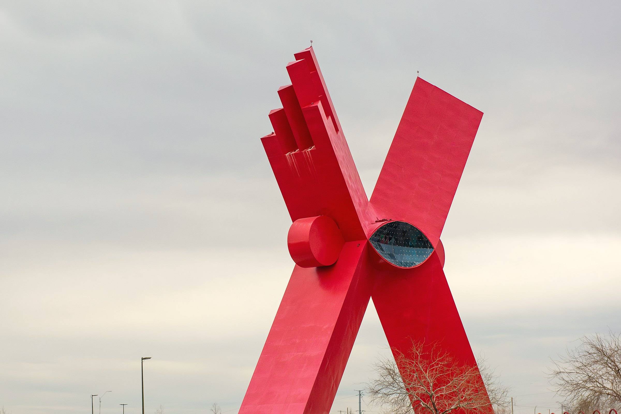The red steel X of the Monumento a la Mexicanidad in Ciudad Juárez against an overcast sky