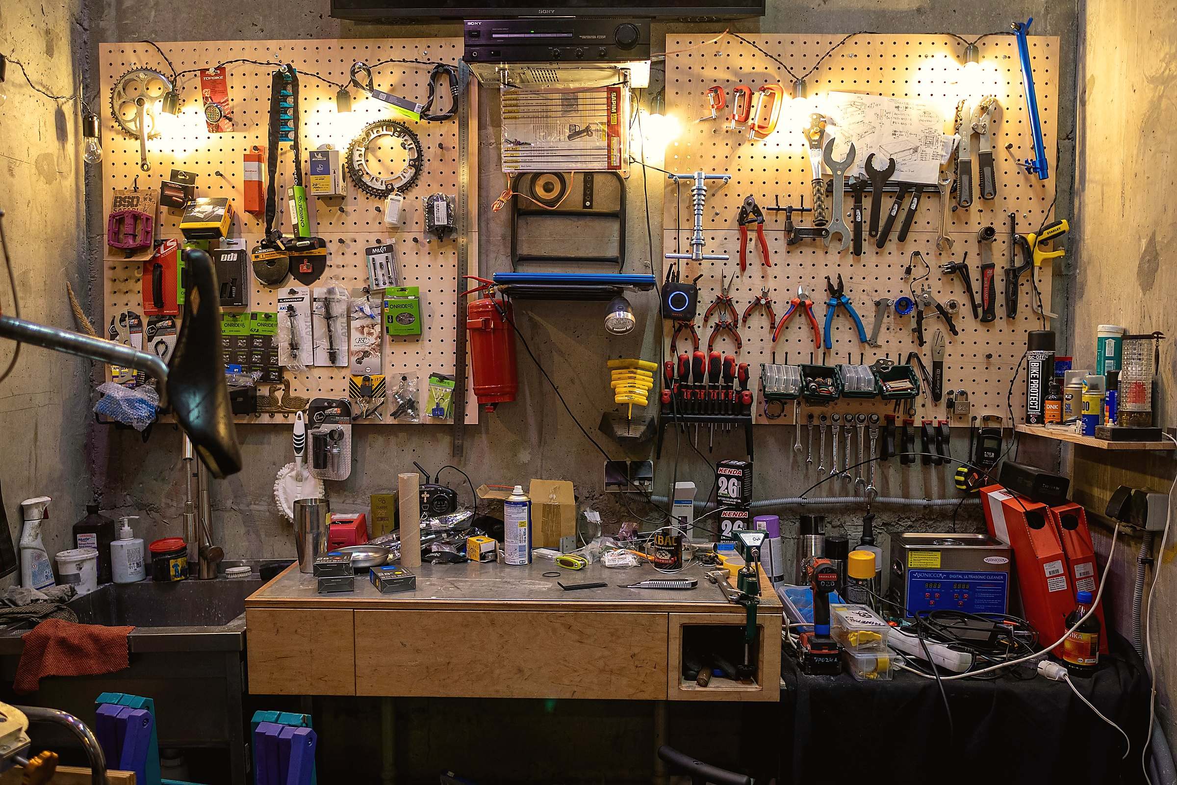 A workshop wall of hand tools on pegboard above a wooden workbench