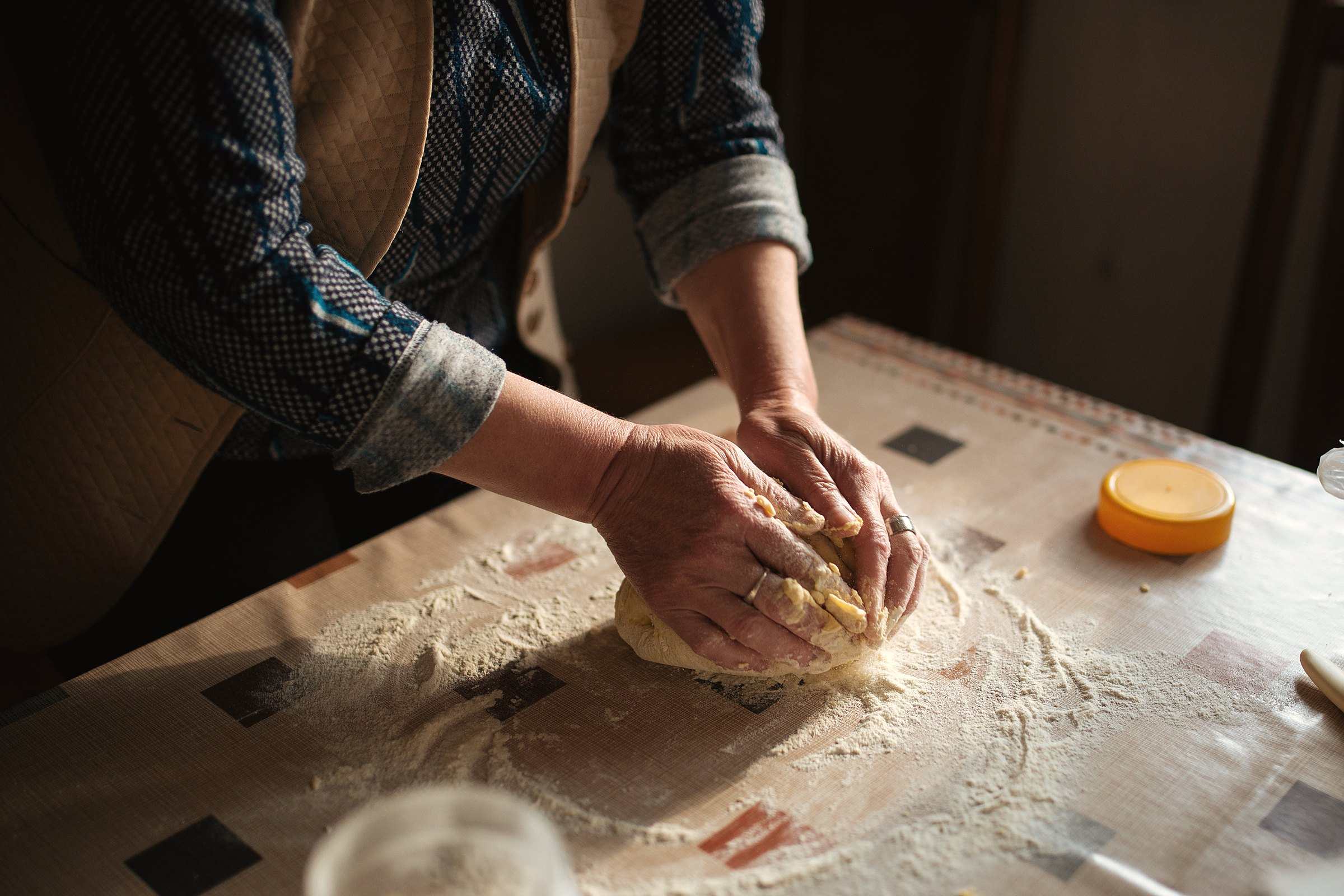 Hands kneading bread dough on a floured kitchen table