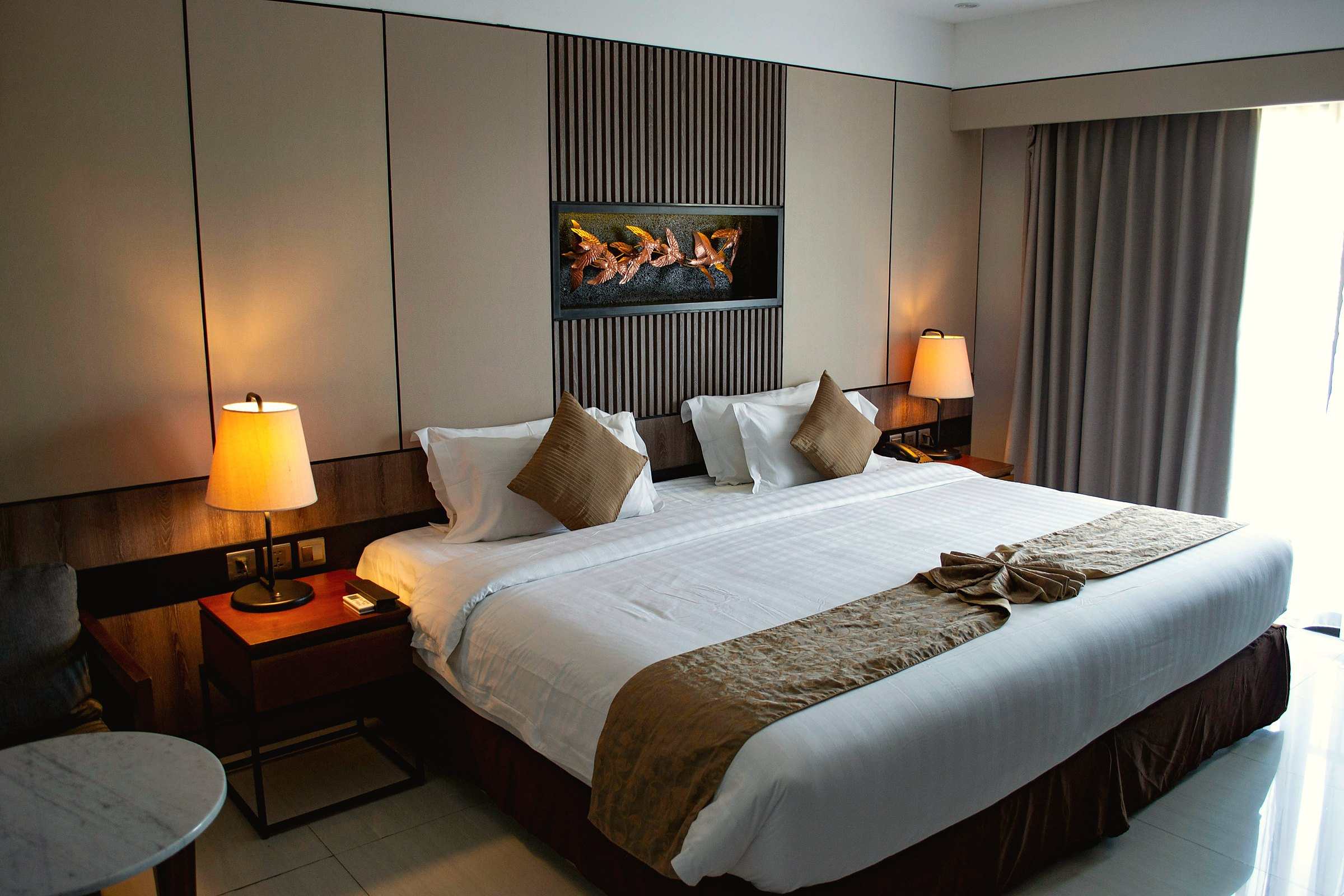 A made hotel bed between two lit bedside lamps