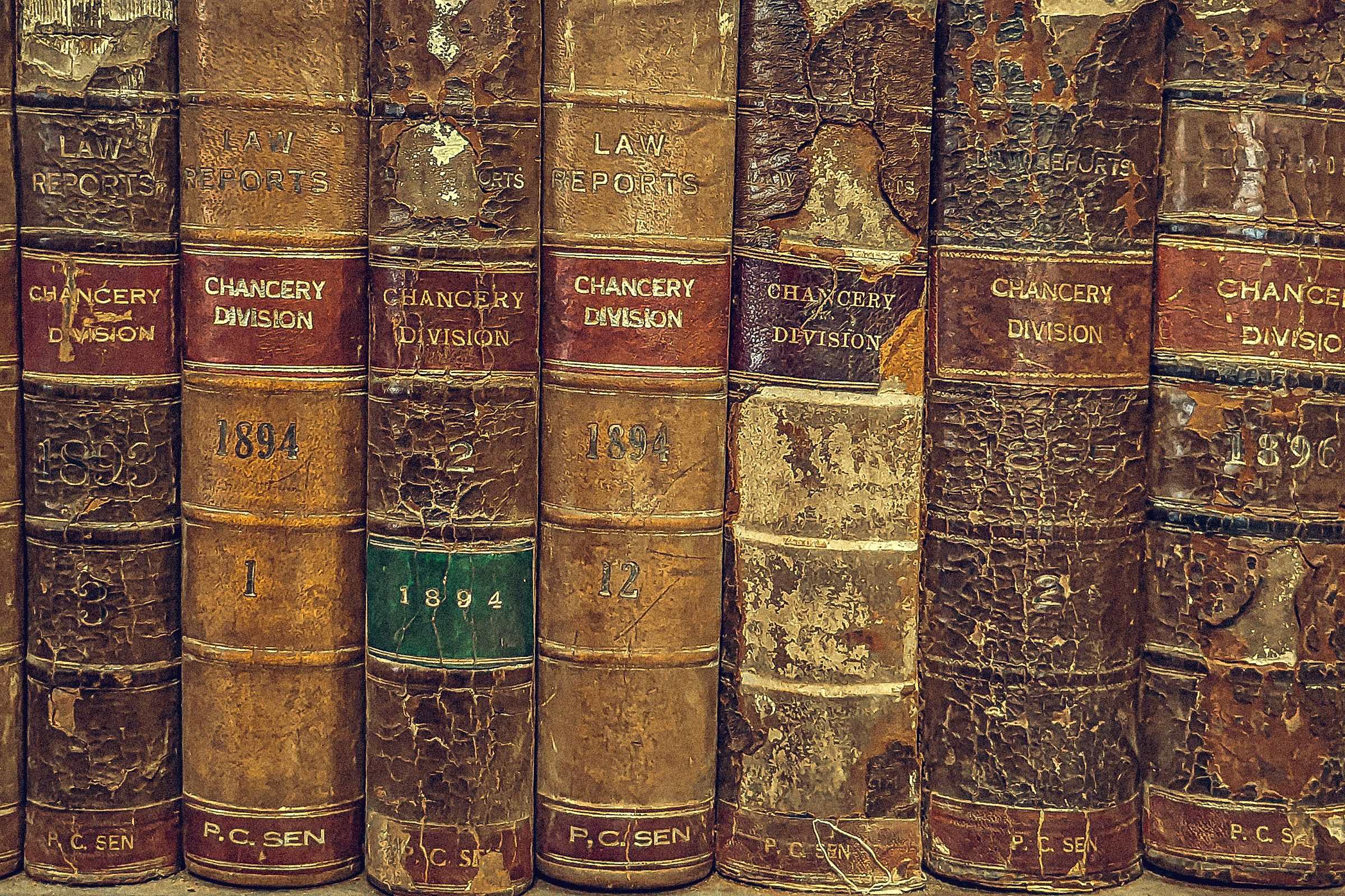 The worn leather spines of antique law books on a shelf