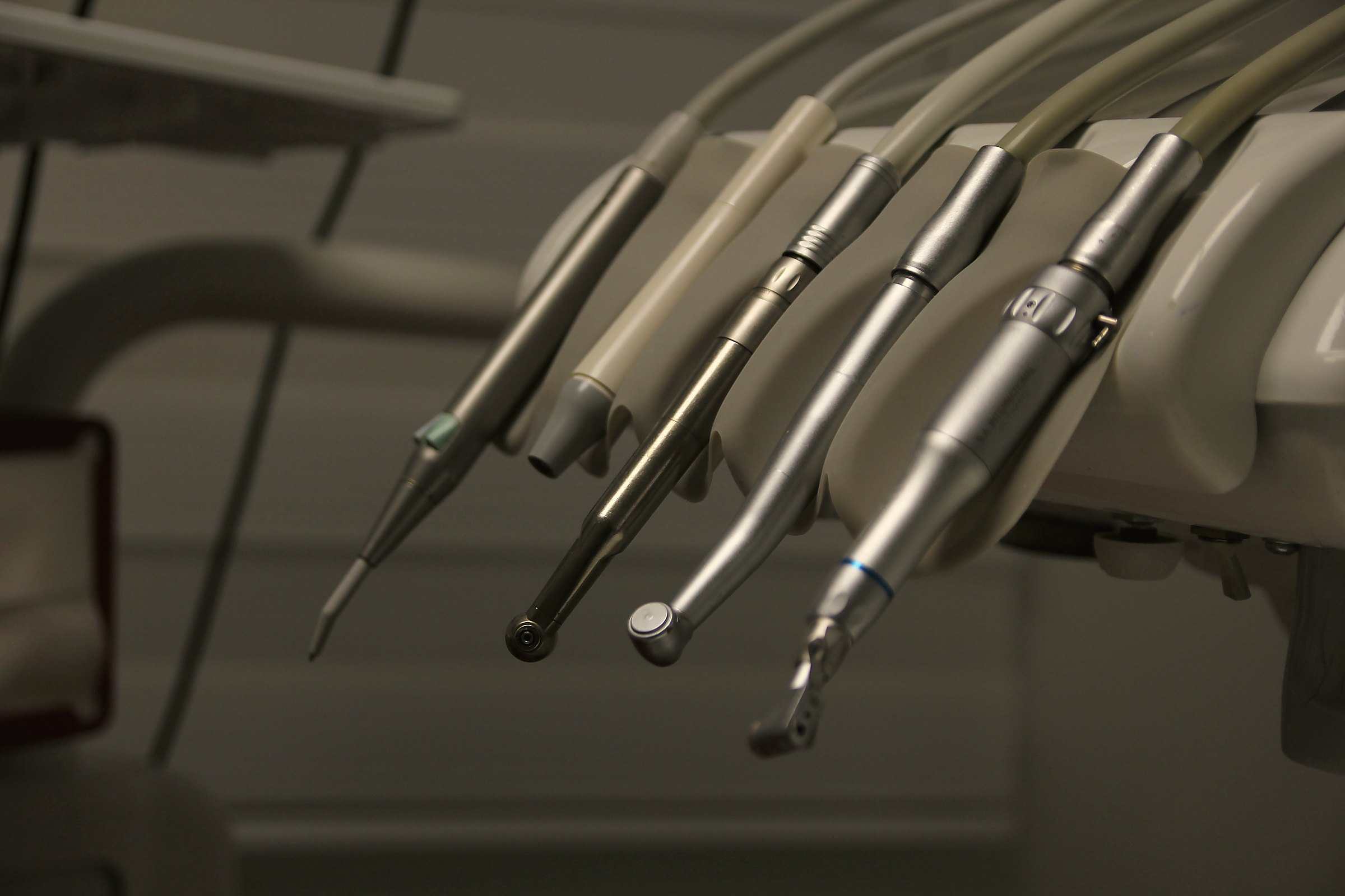 Dental handpieces lined up on the arm of a dental chair