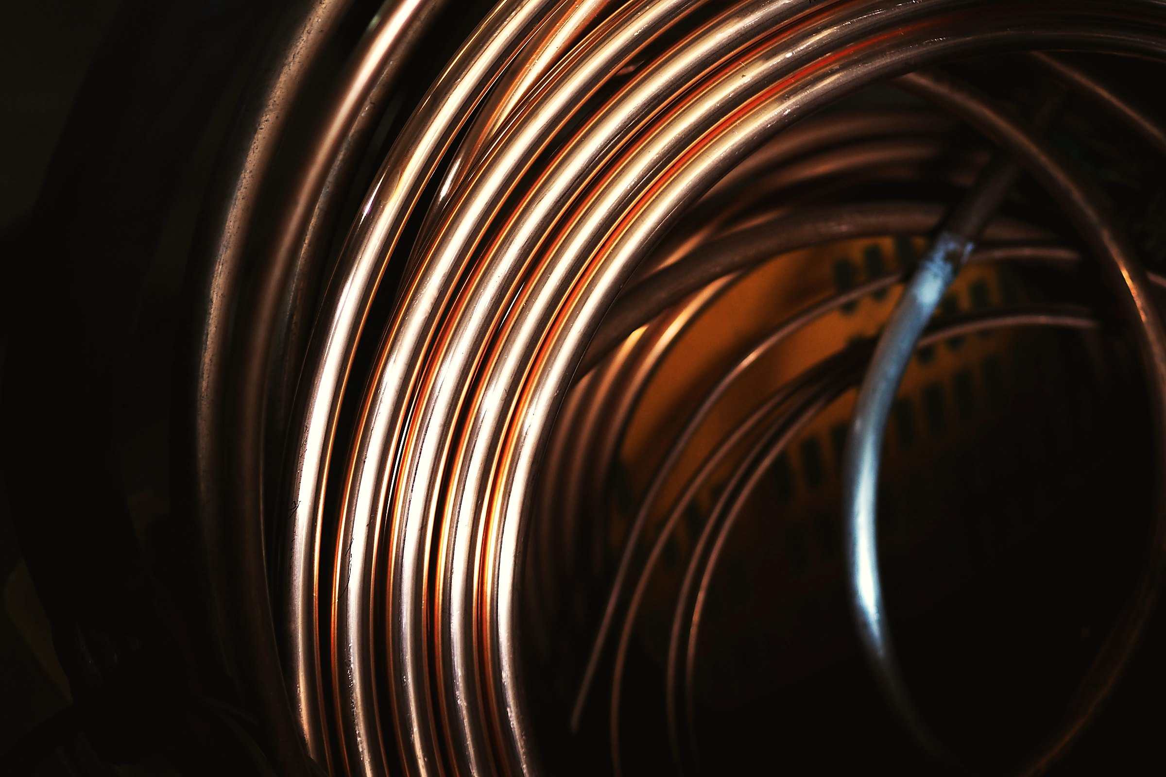 A coil of copper tubing catching warm light against a dark background