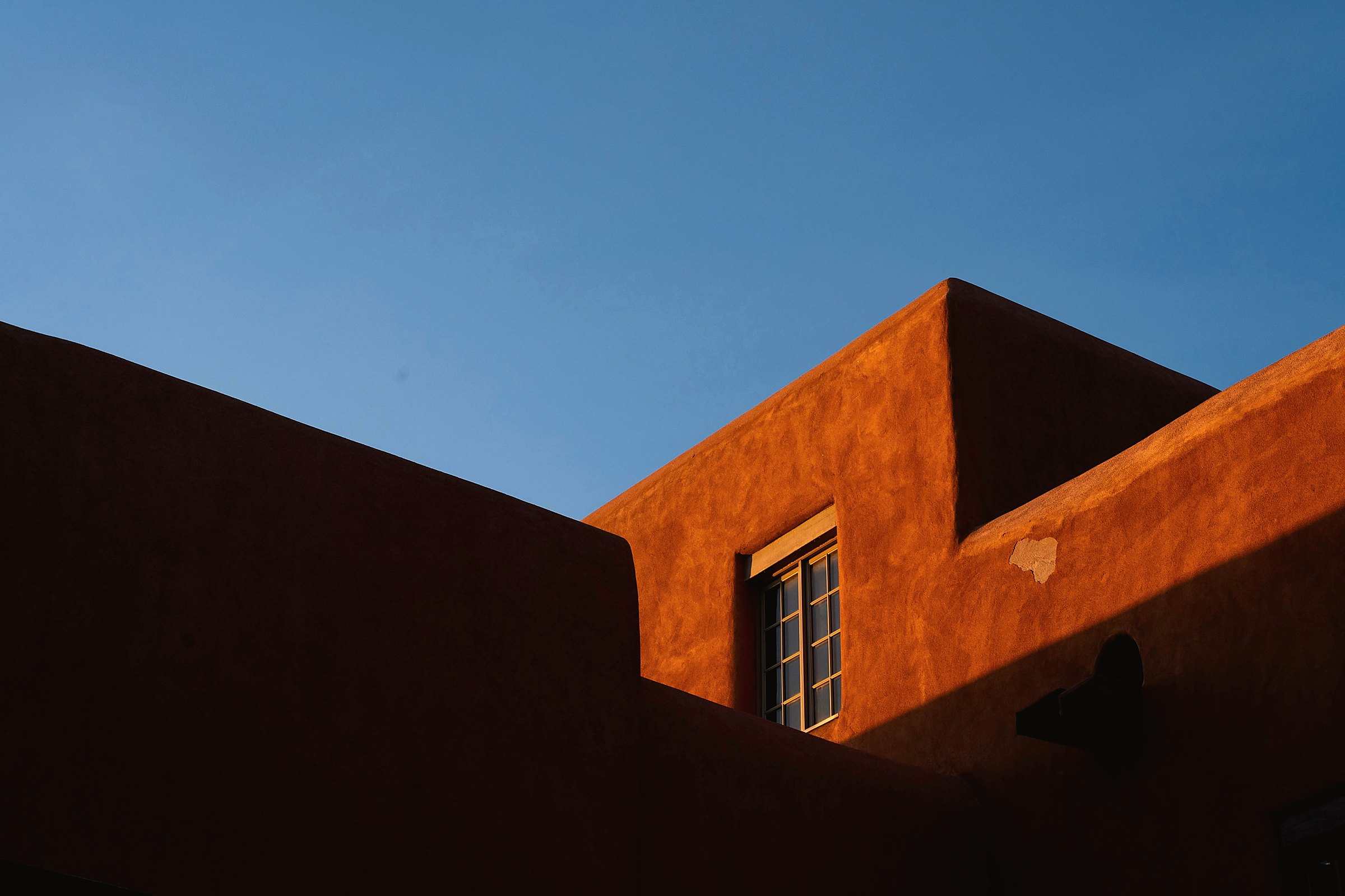 Sunset light on an adobe-style building against a deep blue sky in Santa Fe, New Mexico
