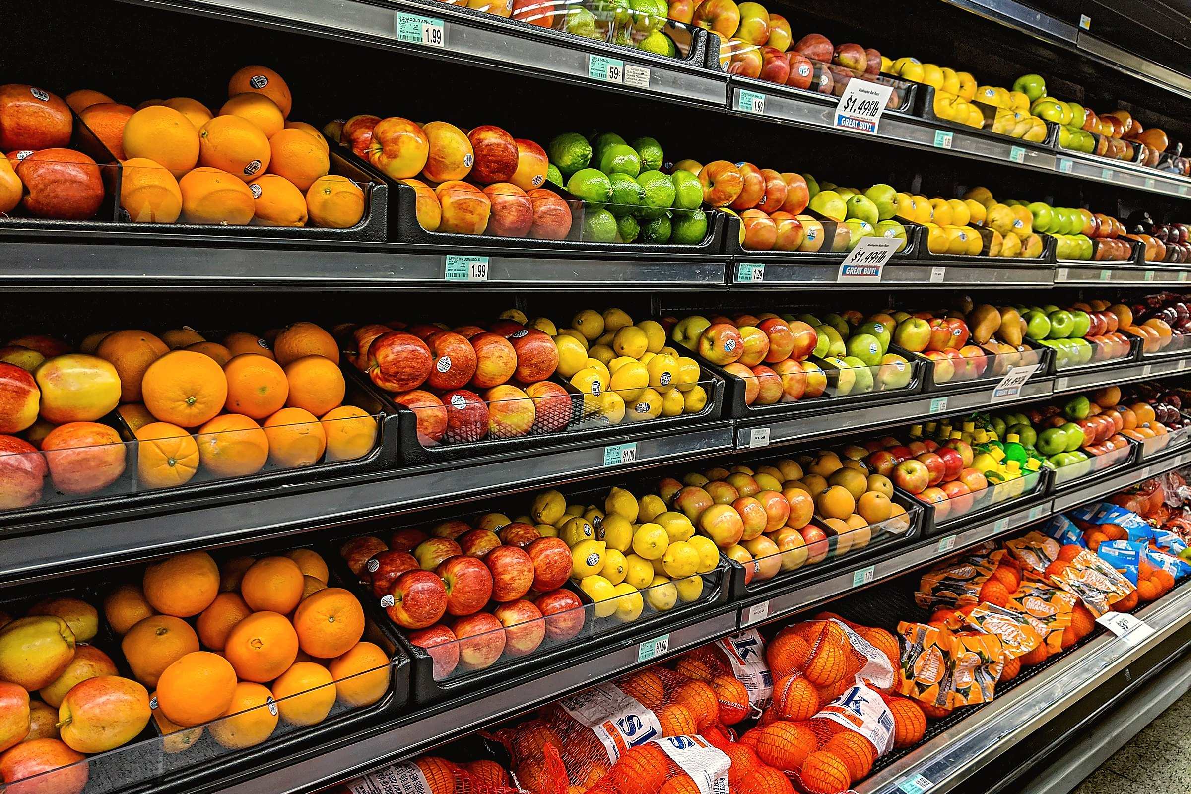 Shelves stacked with oranges, apples and other fruit in a grocery store