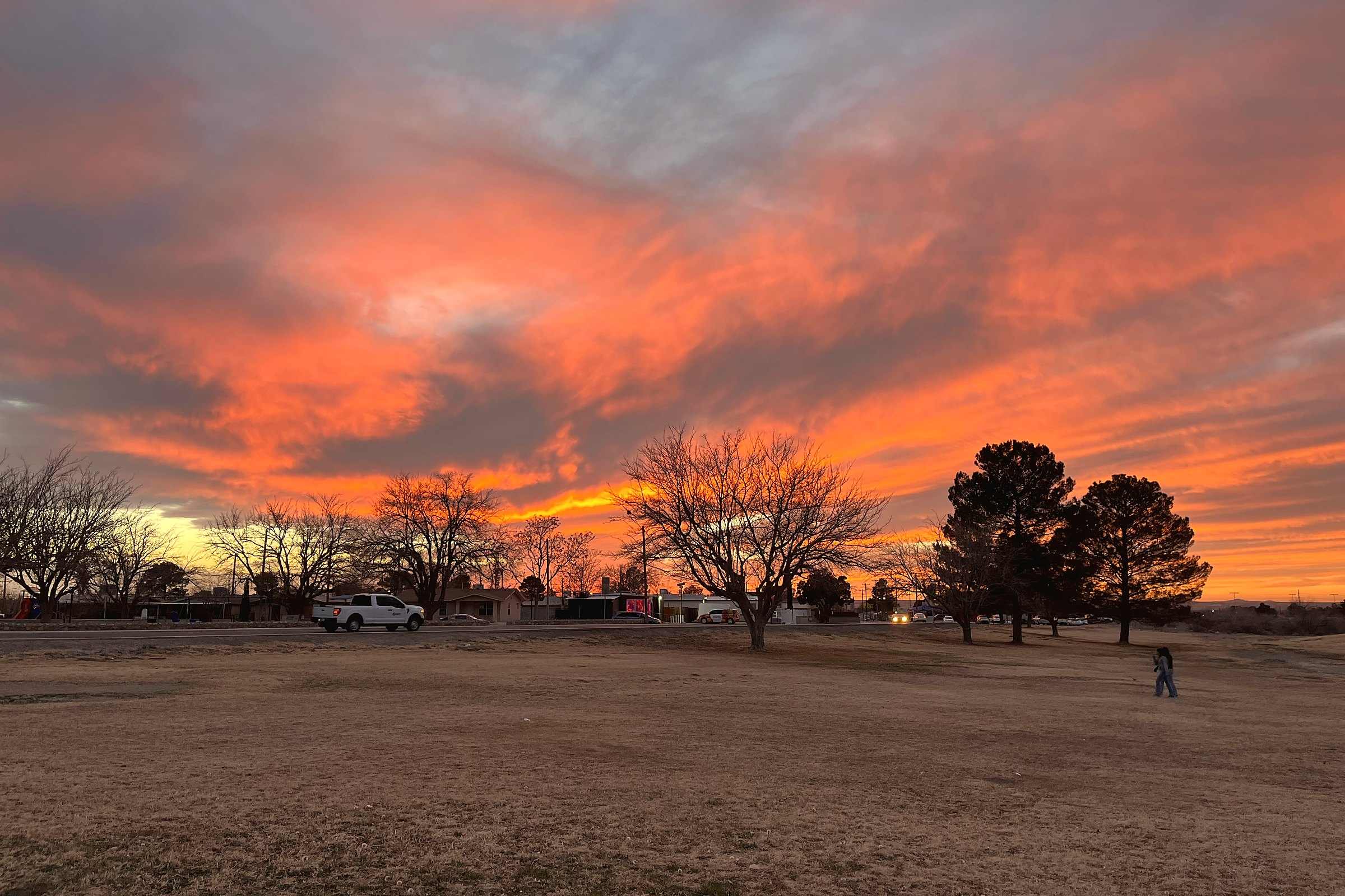 An orange and red sunset over trees and an open field in Anthony, Texas