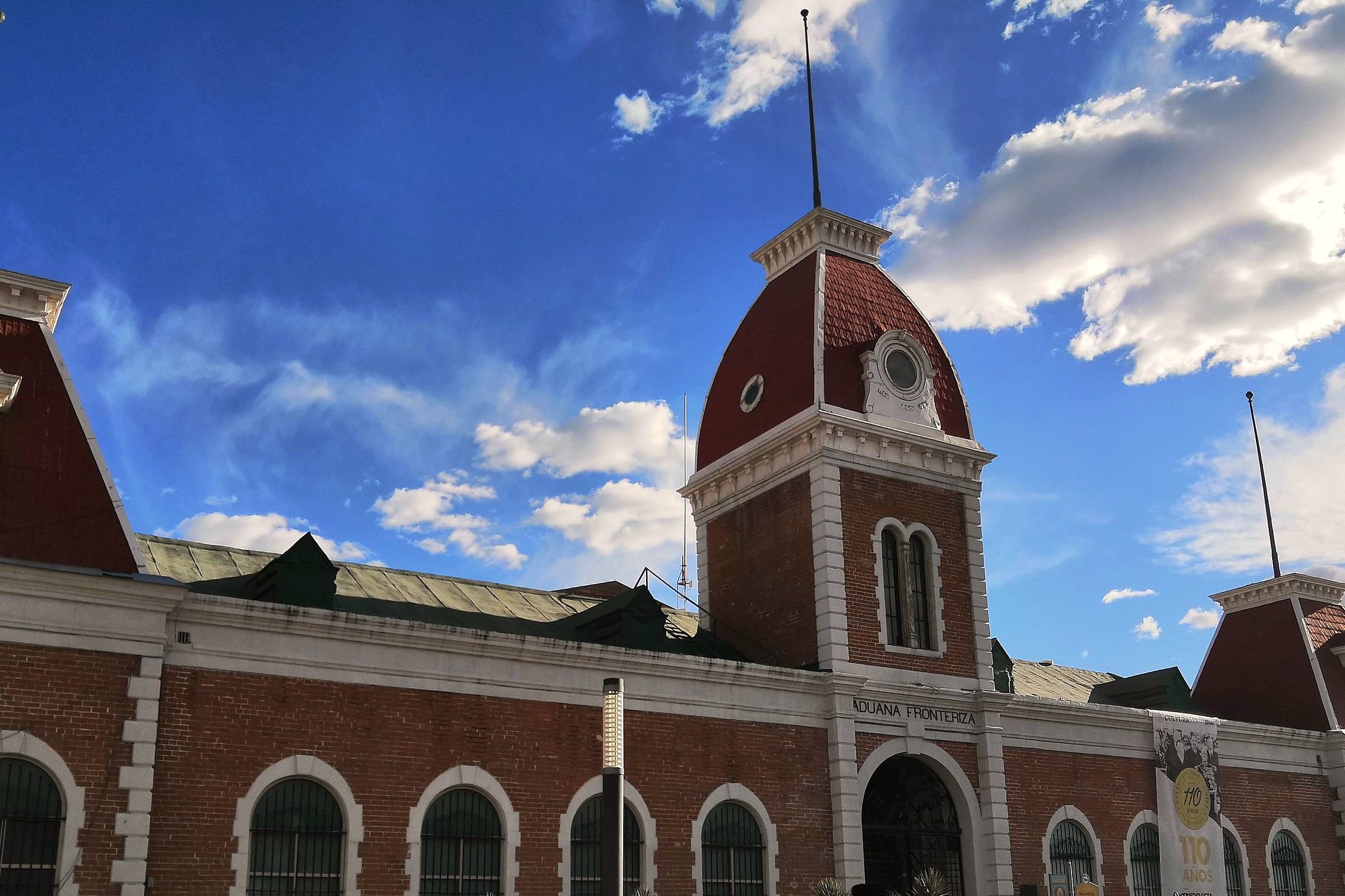 A historic red-brick building with mansard towers in the centro of Ciudad Juárez under a blue sky