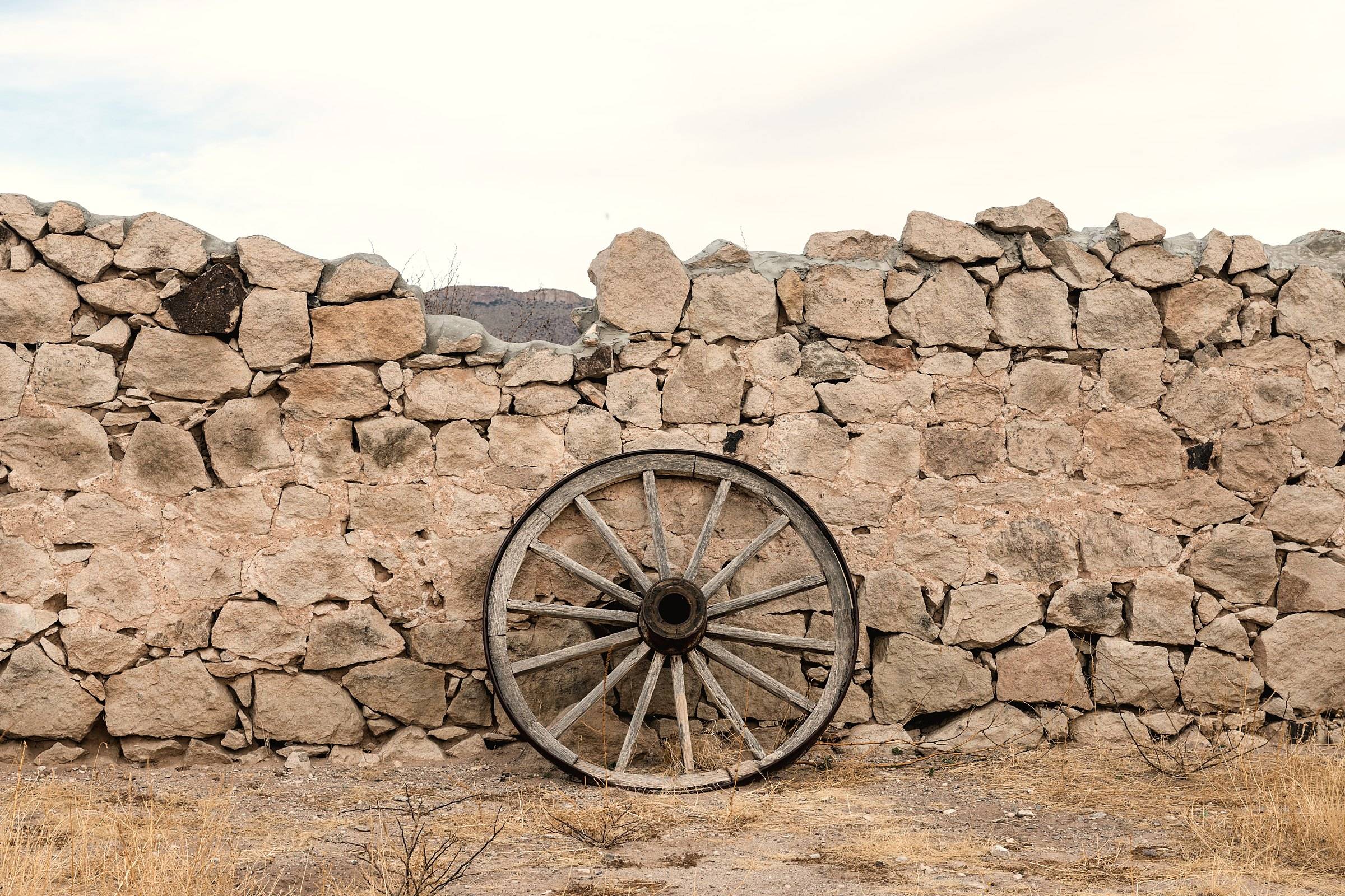 A wagon wheel leaning on a dry-stone wall at Hueco Tanks State Park, El Paso County