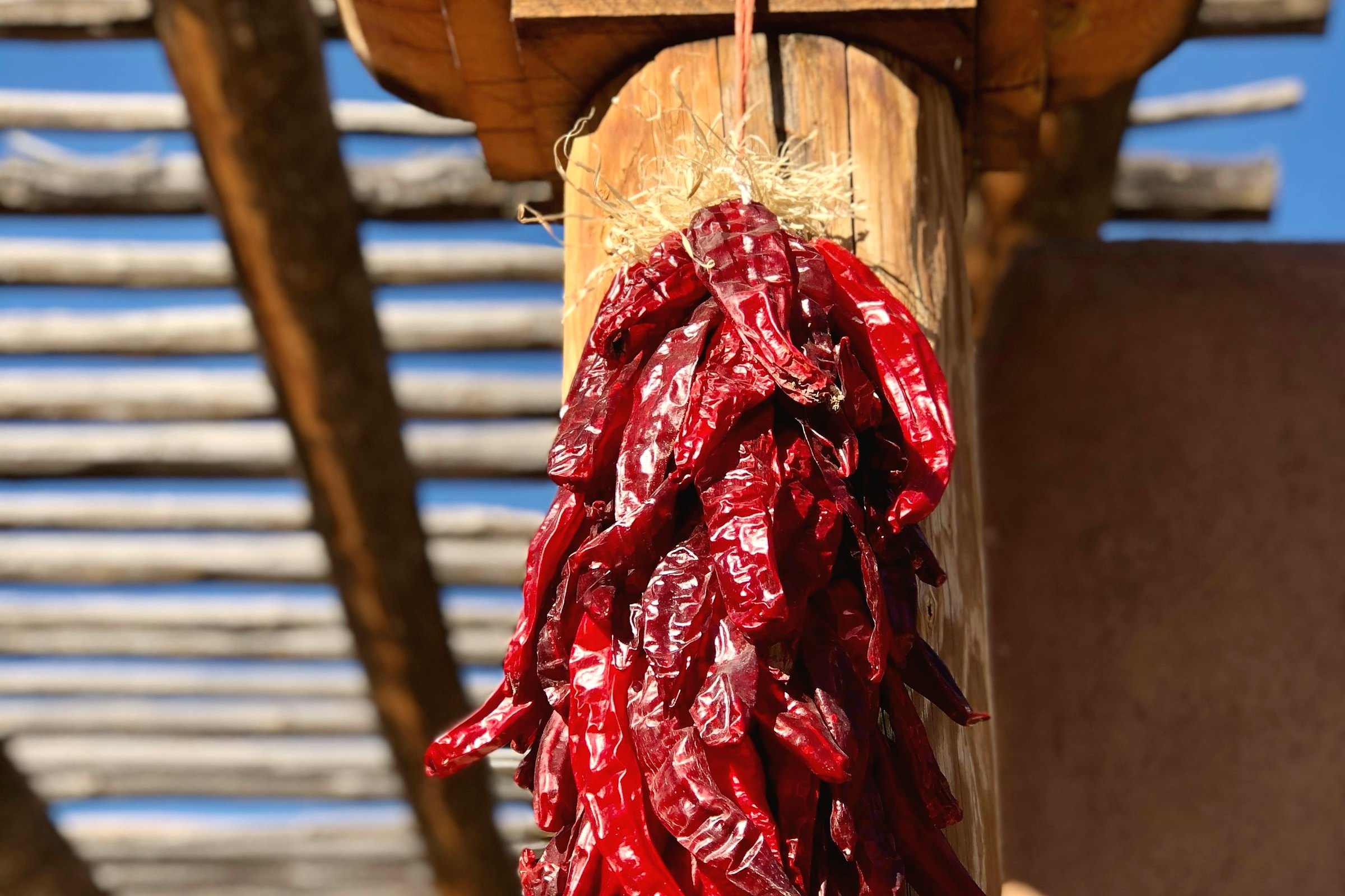 A string of dried red chiles hanging from a carved wooden porch post