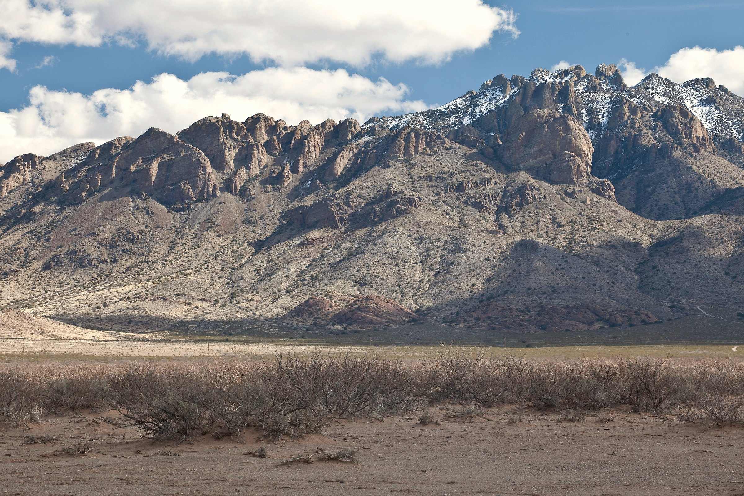 The jagged Florida Mountains of Luna County, New Mexico, under a blue sky with clouds