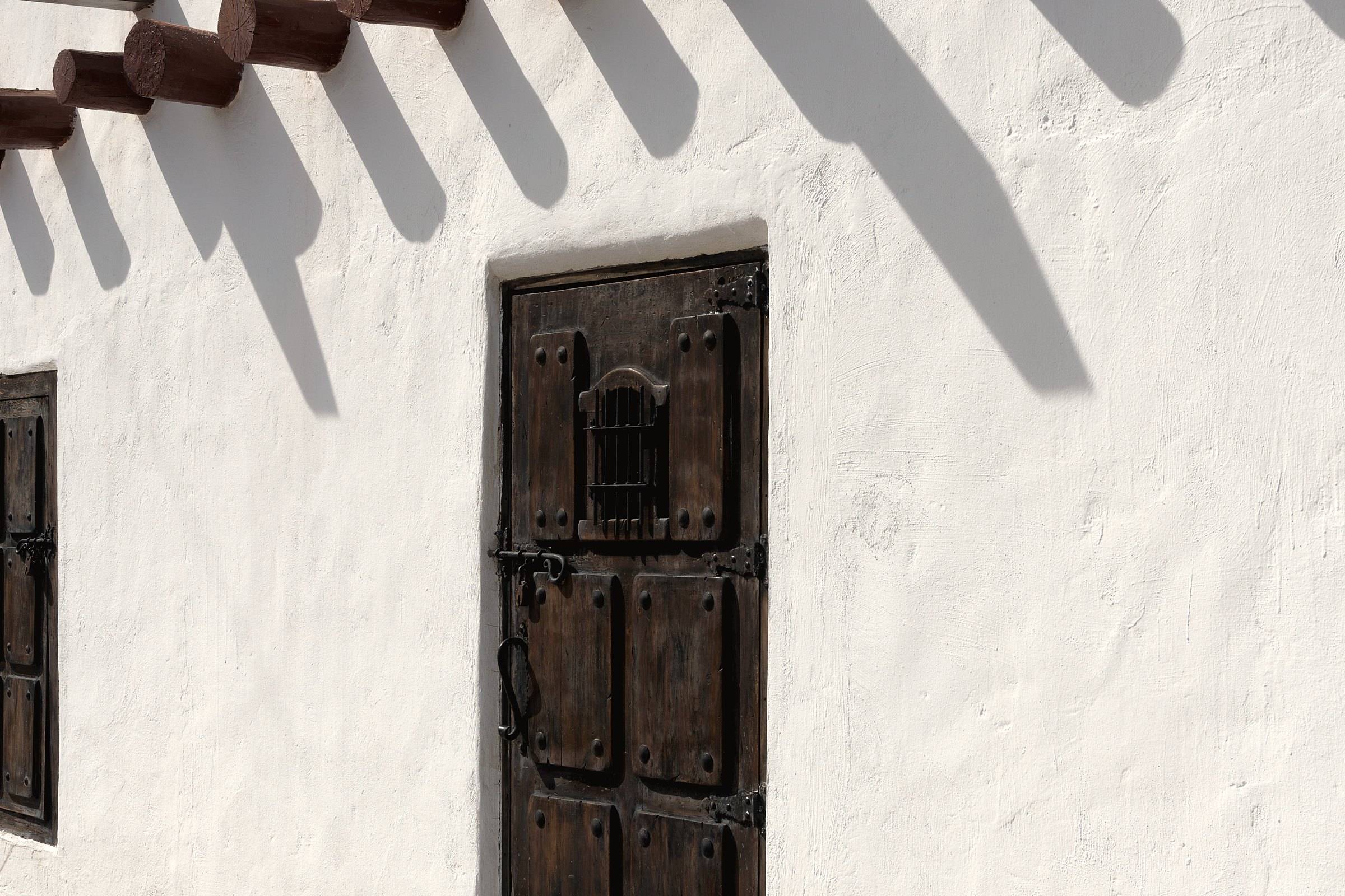 A weathered wooden door in a whitewashed wall in San Elizario, Texas