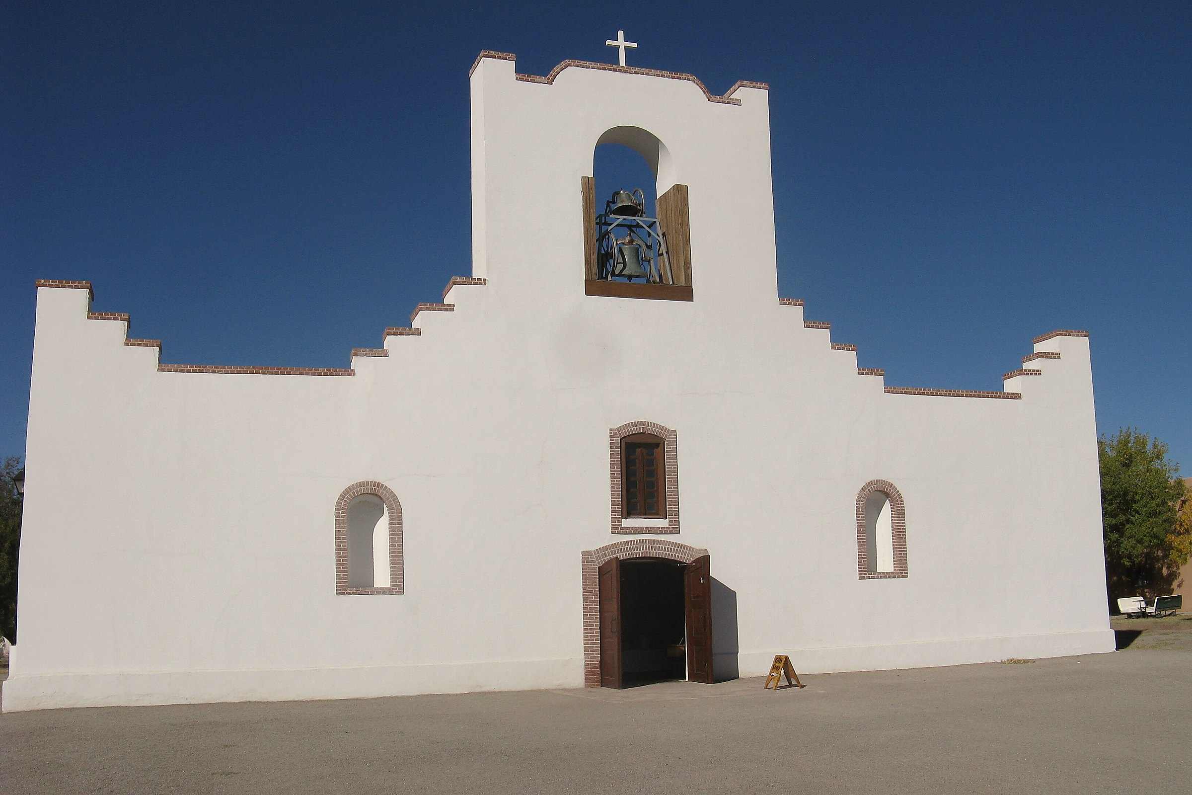 The white facade and bell gable of the Socorro Mission in Socorro, Texas, under a deep blue sky