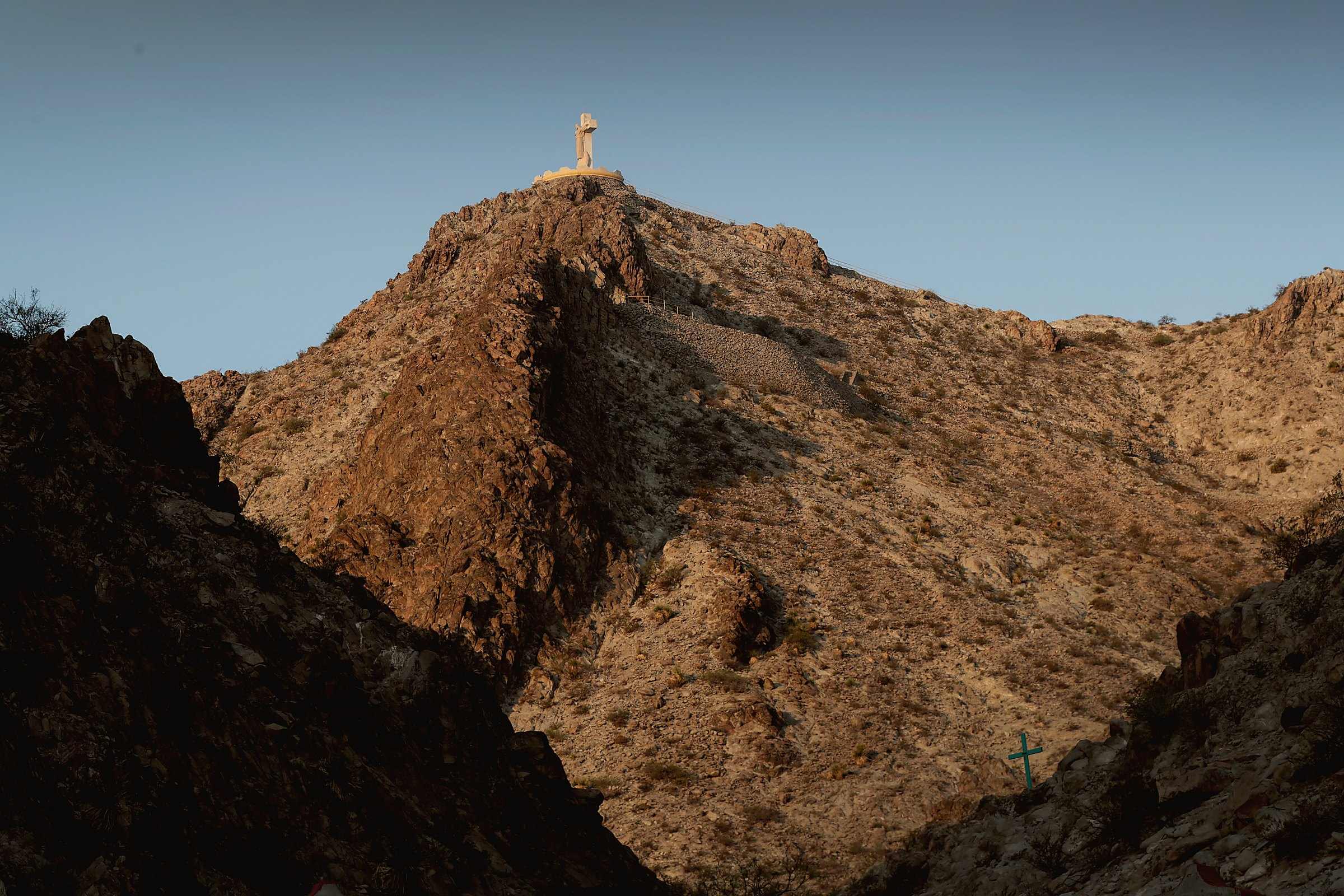 The cross atop Mount Cristo Rey near Sunland Park, New Mexico, above sunlit desert rock