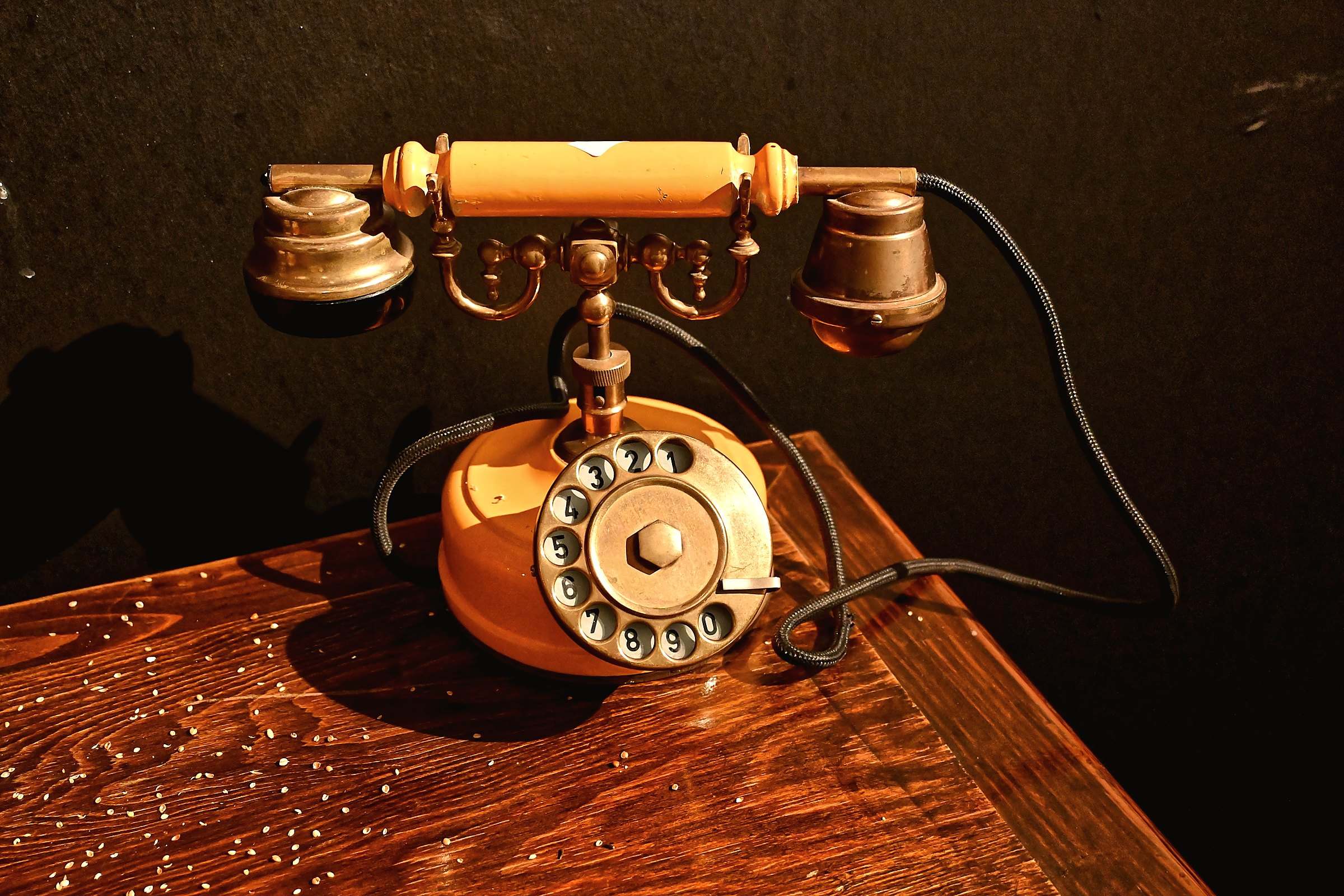 An antique brass rotary telephone on a polished wooden table
