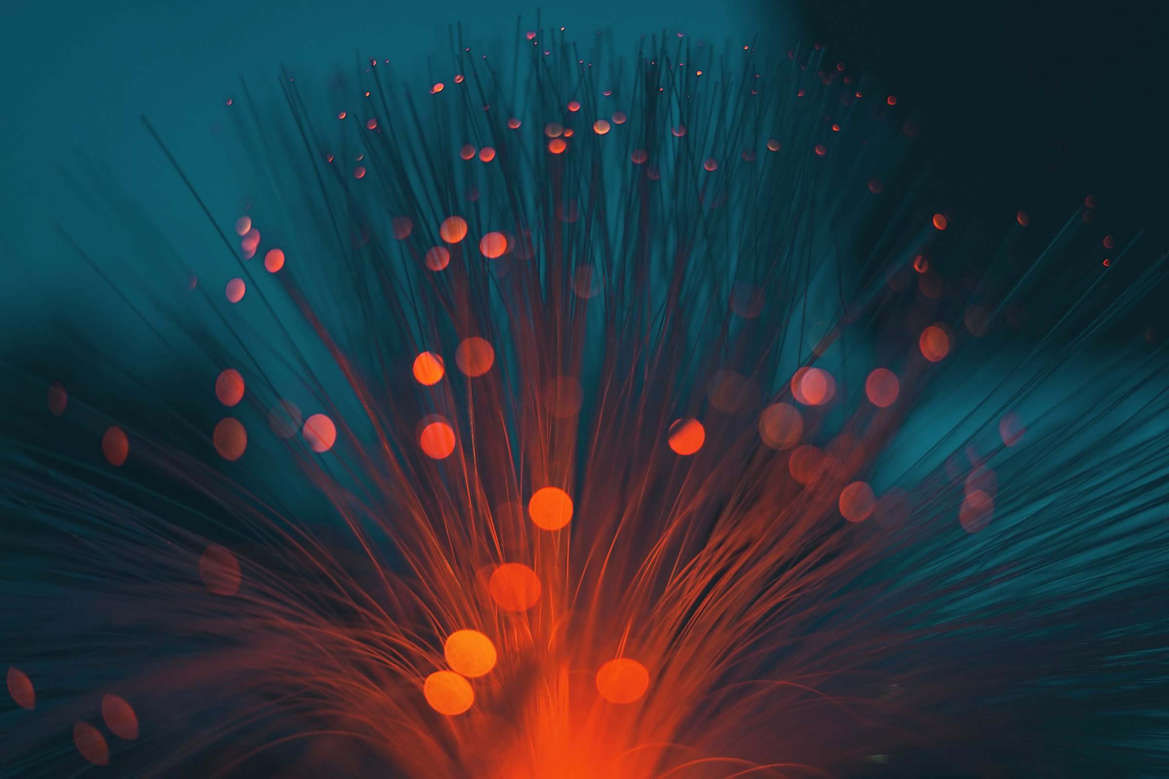 Fine glowing strands fanning out in orange and teal light