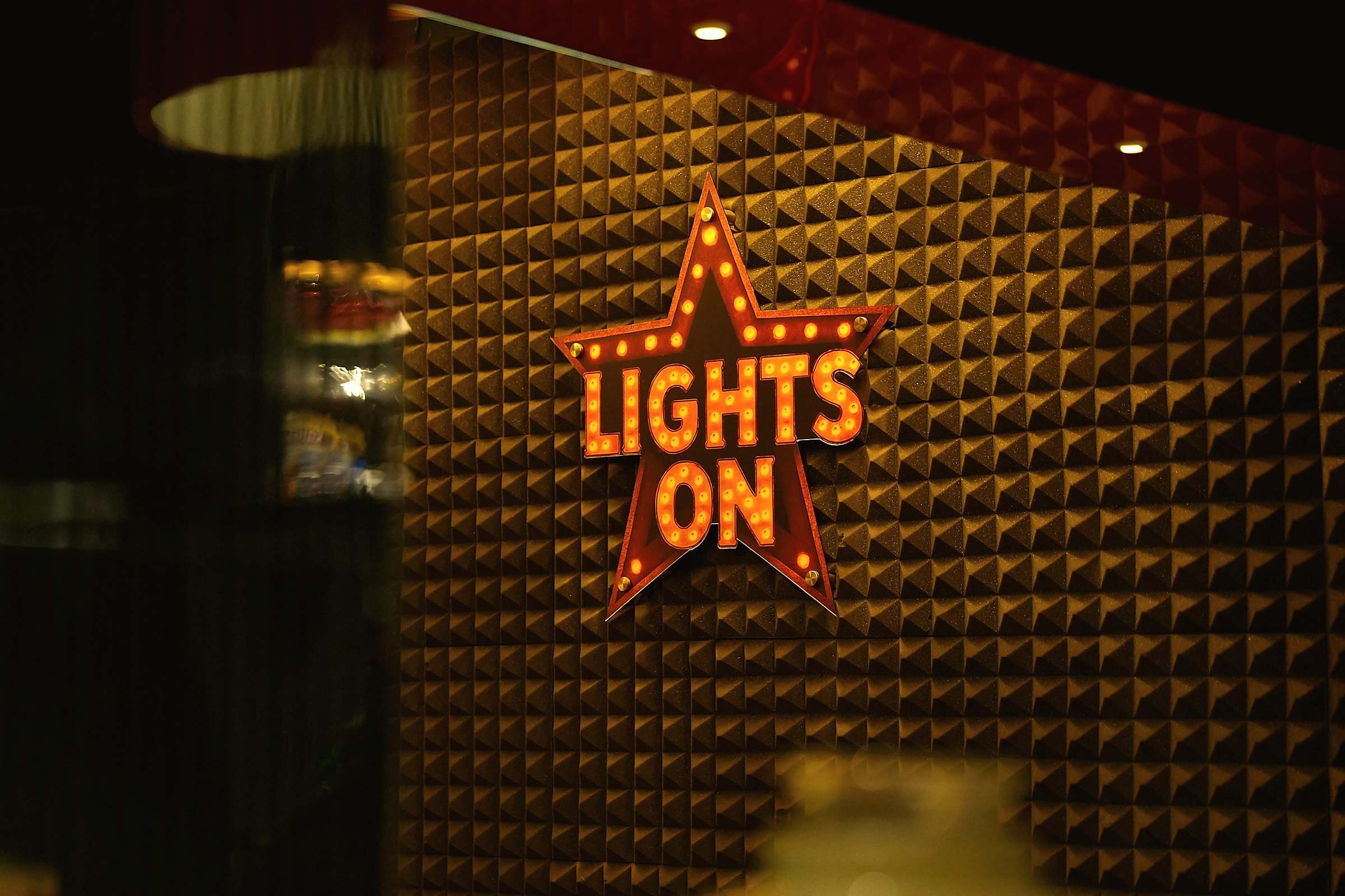 A star-shaped marquee sign reading "lights on" glowing on a dark textured wall