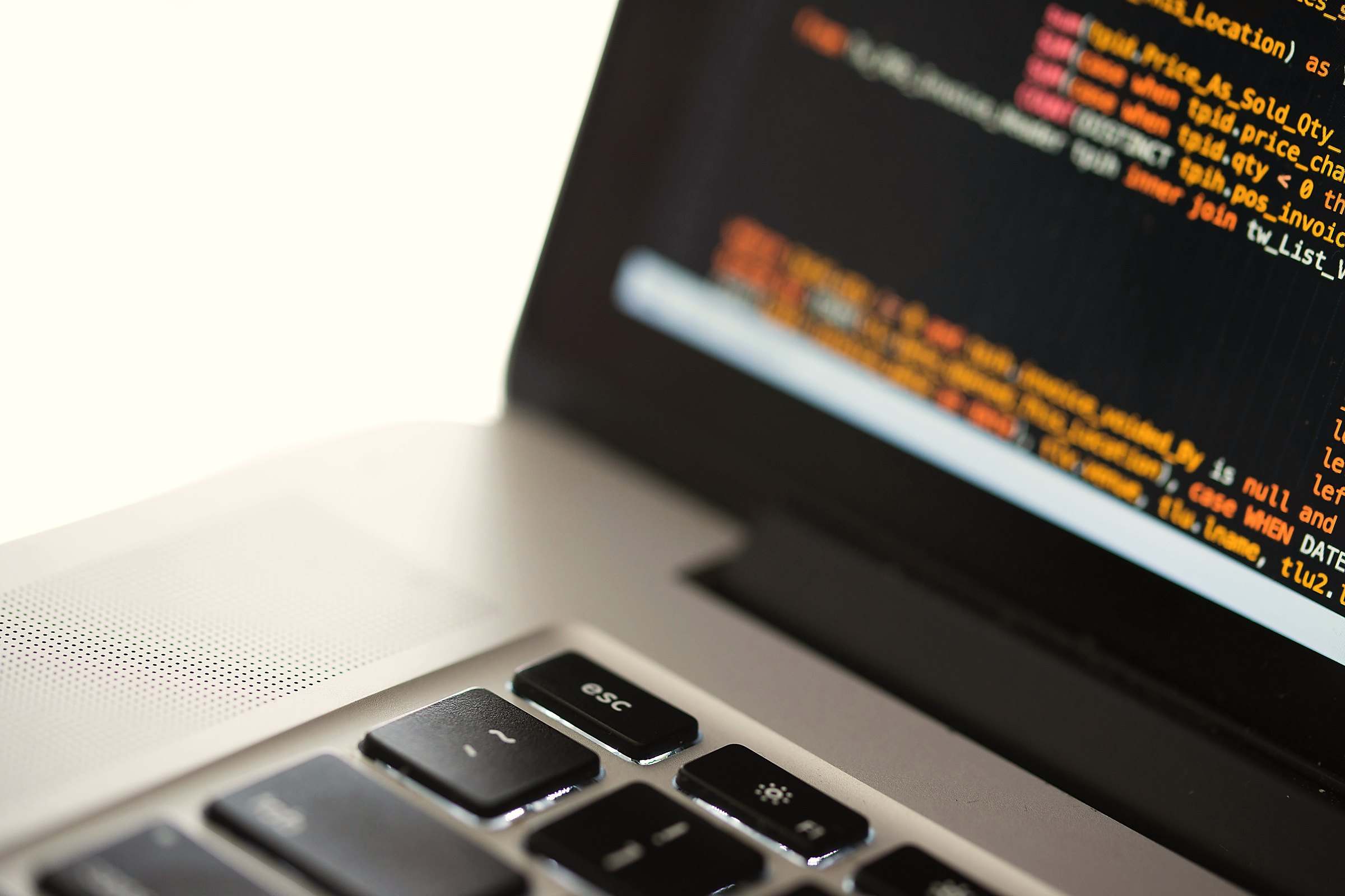 Lines of colourful code on the screen of a silver laptop